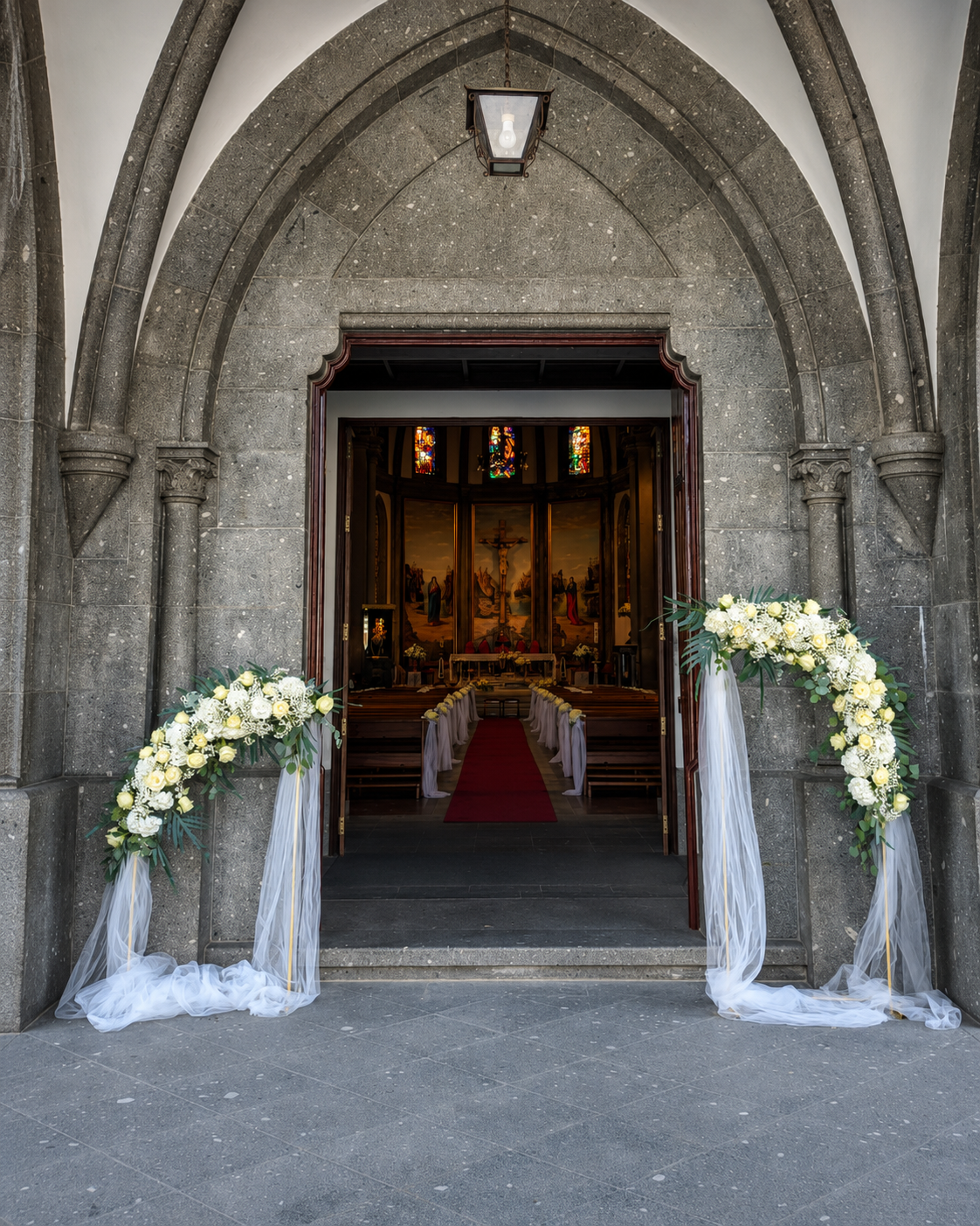 Entrada de igreja em pedra decorada com estruturas florais brancas e verdes para casamento