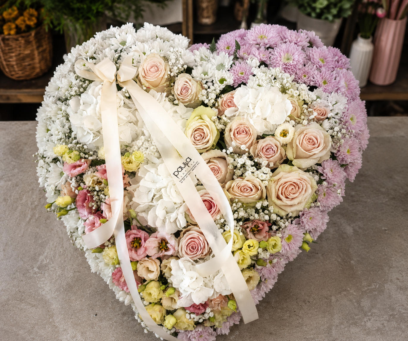 Homenagem floral em forma de coração com rosas, hortênsias e flores em tons de branco e rosa