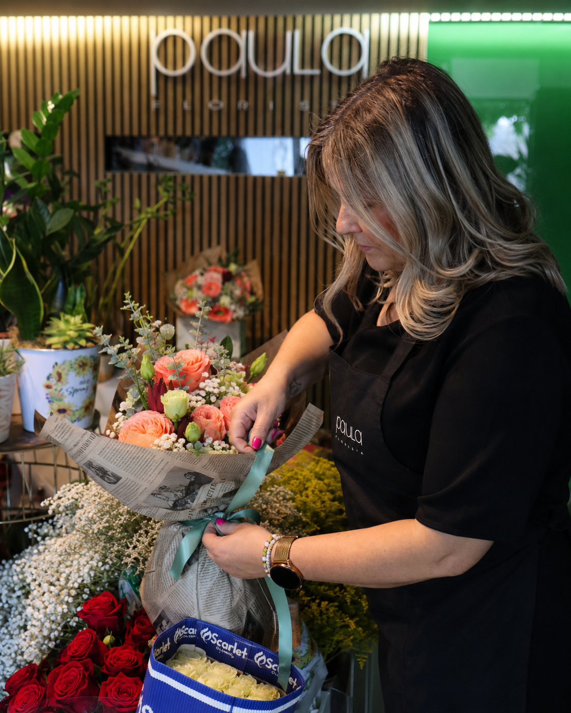 Paula Florista a ajustar a fita e a finalizar um ramo de flores na sua loja em Fafe