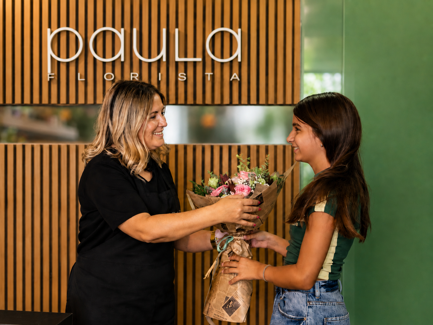 Paula Florista a entregar um ramo de flores a uma cliente na sua loja em Fafe